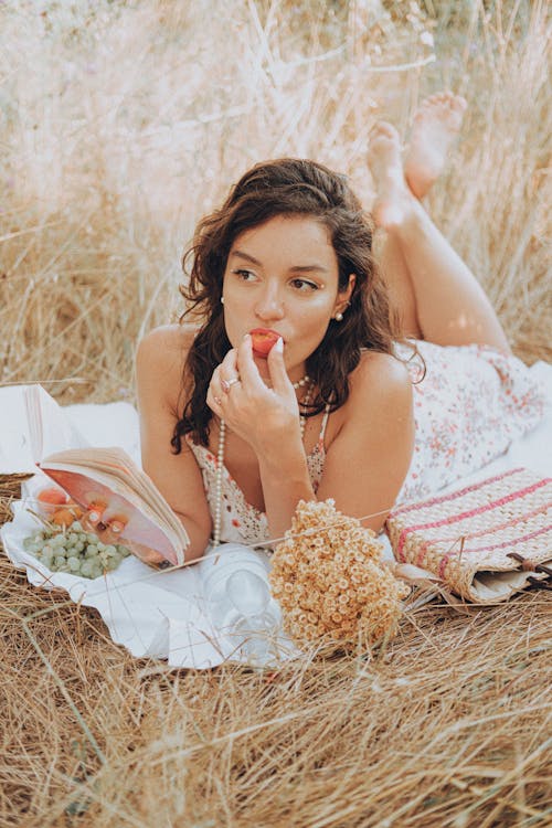 Woman Lying Down on Picnic Blanket and Eating