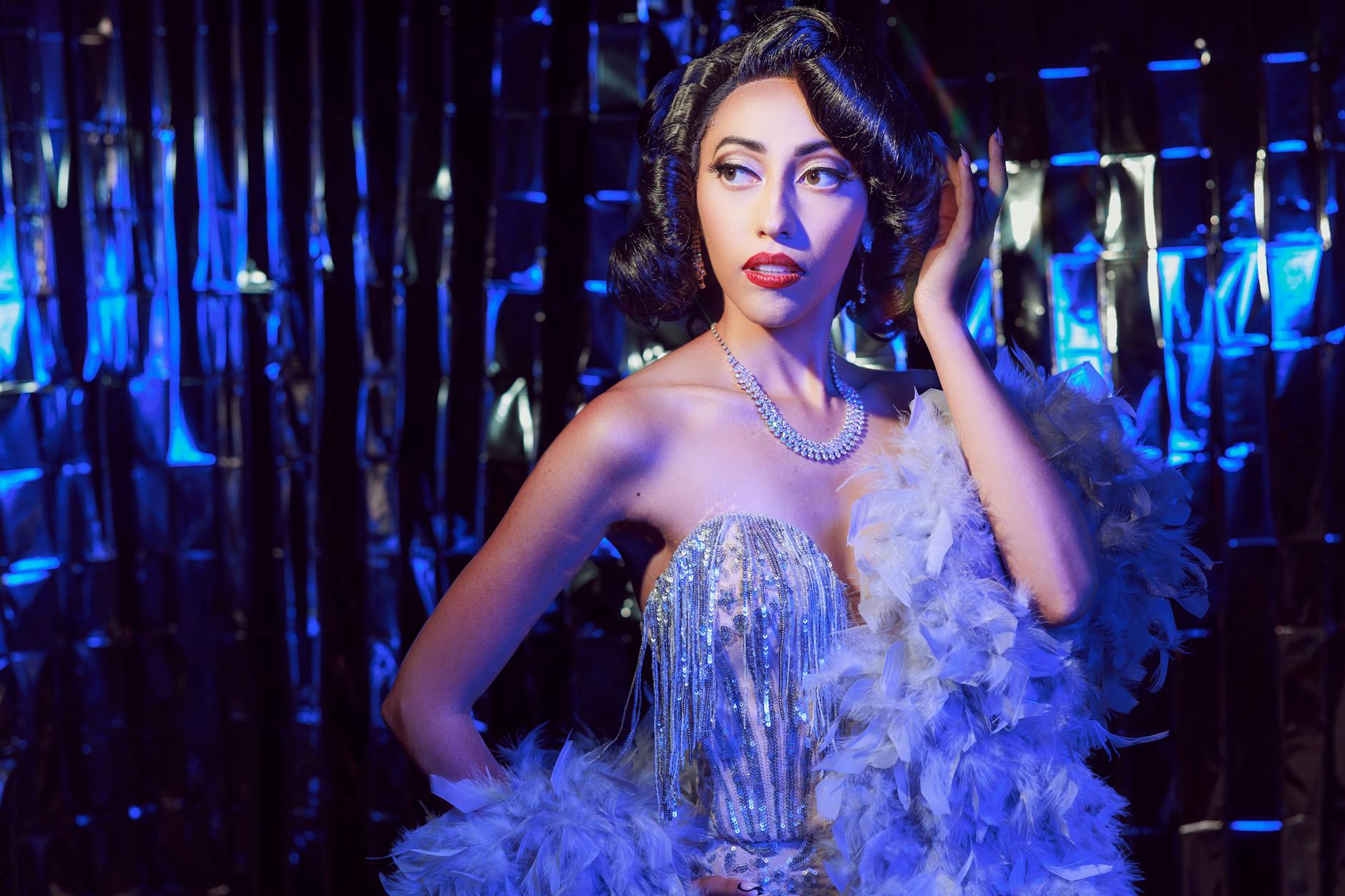 Glamorous woman in vintage attire with blue lighting backdrop.