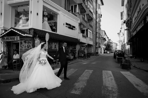 Free Newlywed couple elegantly crossing a city street in black and white. Stock Photo