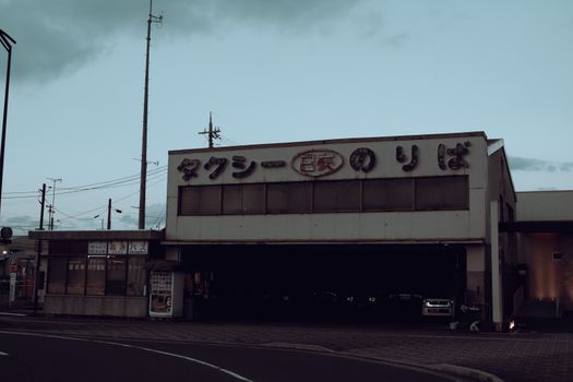 Vintage taxi station with Japanese signs captures a serene urban setting at dusk.