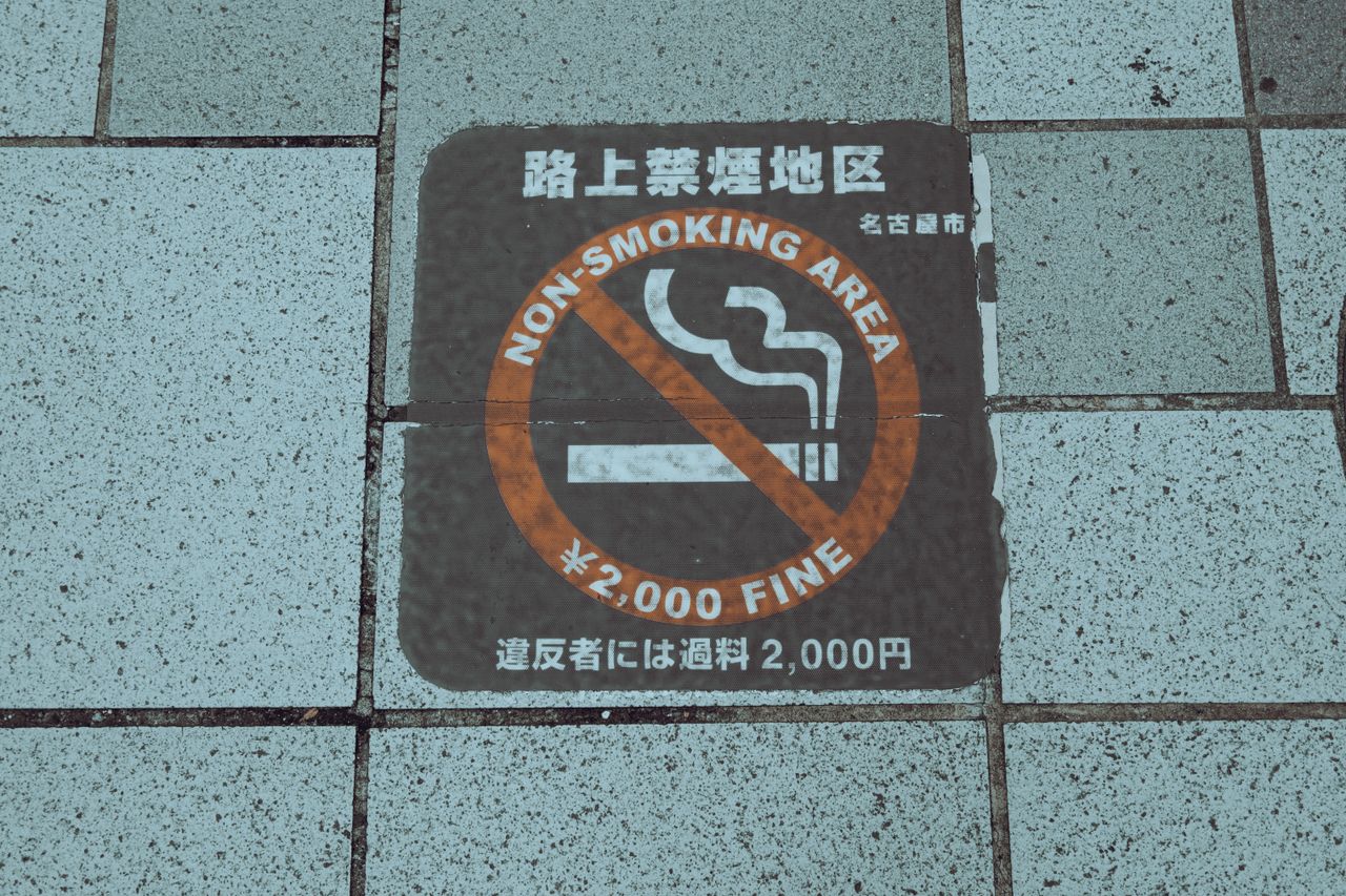 close up of a non smoking area sign on a city sidewalk highlighting a