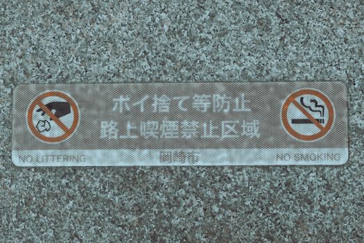 Close-up of a Japanese sign prohibiting littering and smoking in an urban area.