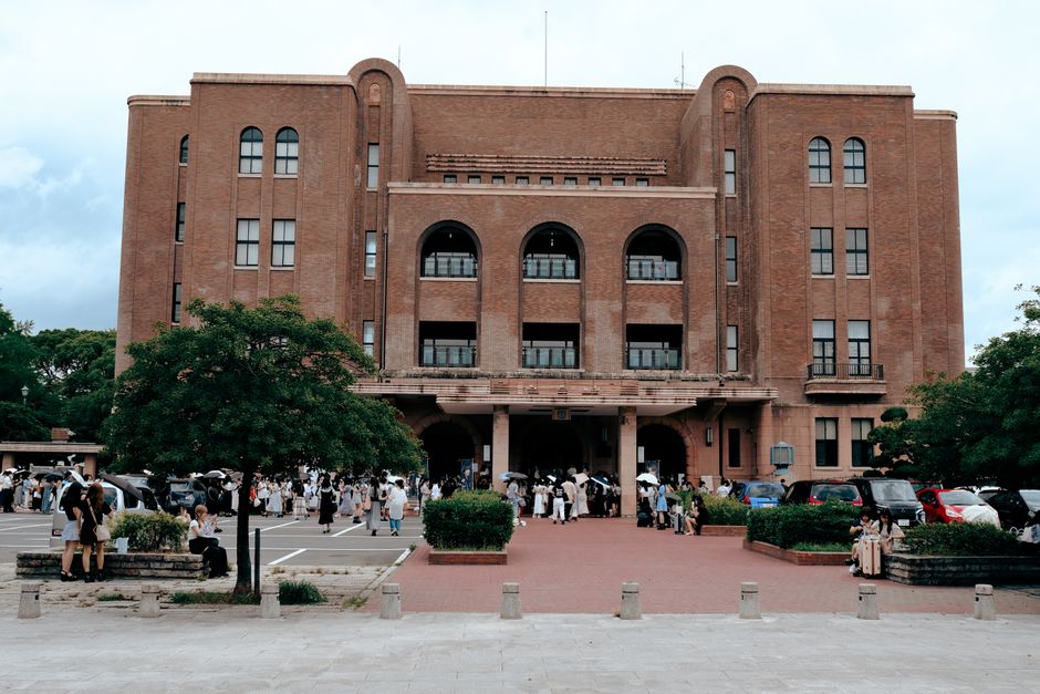 Exterior view of Nagoya Civic Assembly Hall with people gathering outside on a bright day.