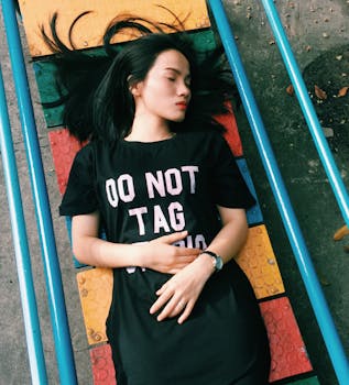 夏季，一位穿着黑色连衣裙的亚洲女性在色彩缤纷的城市操场上放松身心