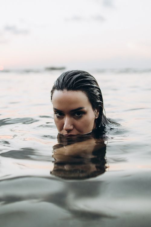 Free Woman partially submerged in tranquil waters at twilight, exuding calm and tranquility. Stock Photo