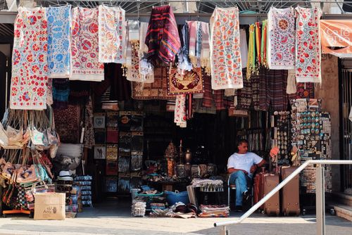 Free A bustling market stall displaying colorful tapestries and souvenirs in an outdoor bazaar setting. Stock Photo