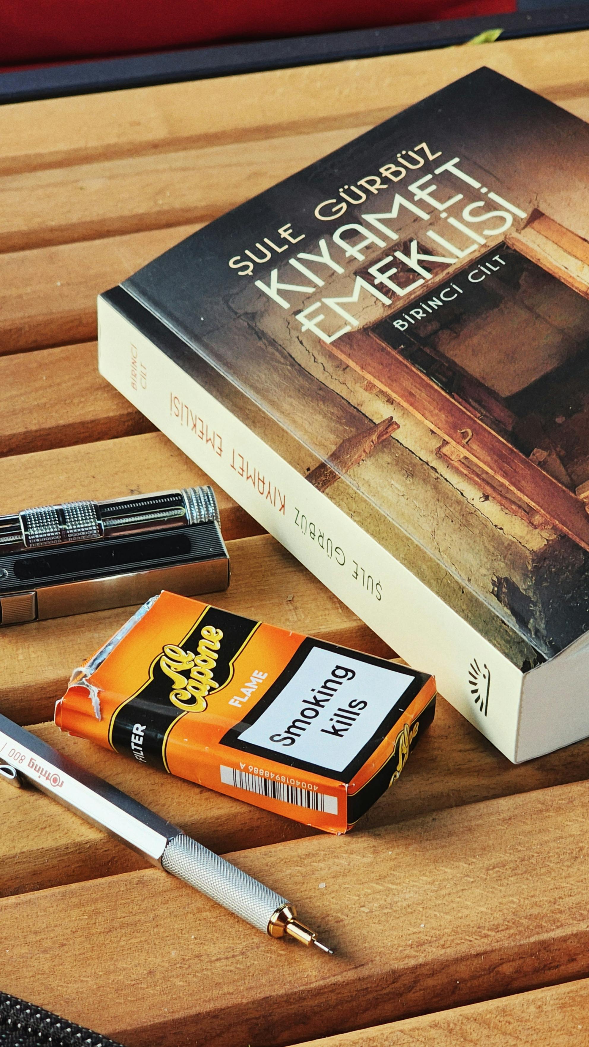 Close-up of a book and cigarette pack on a wooden table. Unique everyday still life shot.