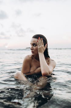 A woman enjoying a serene moment in the ocean during sunset, creating a tranquil and relaxing scene.