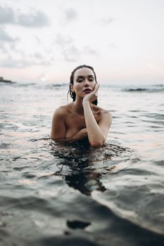 A woman enjoys a tranquil moment in the sea at sunset, embodying relaxation and peace.