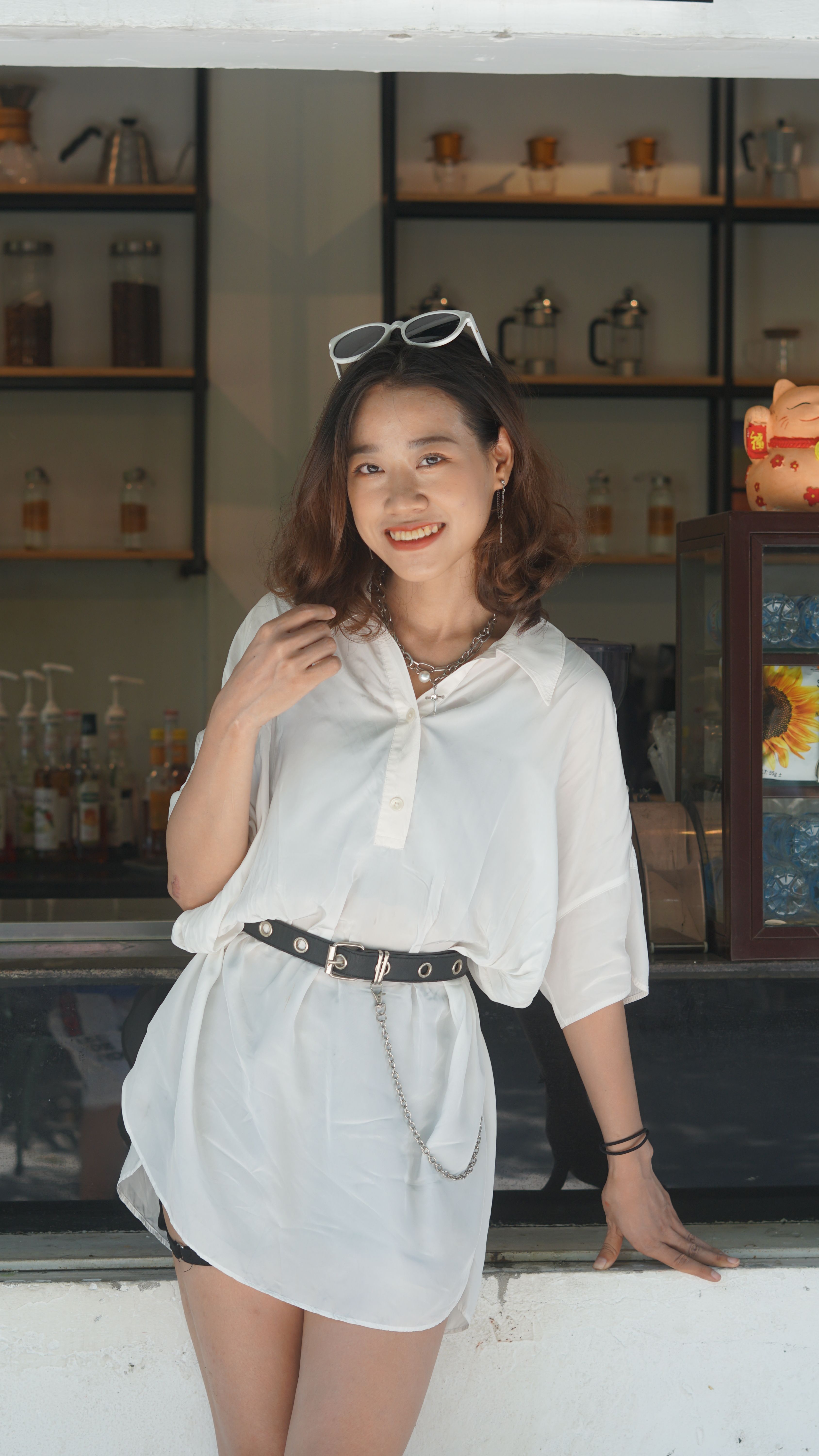 Bright and cheerful woman in white dress leaning on a cafe counter, adding warmth and charm.