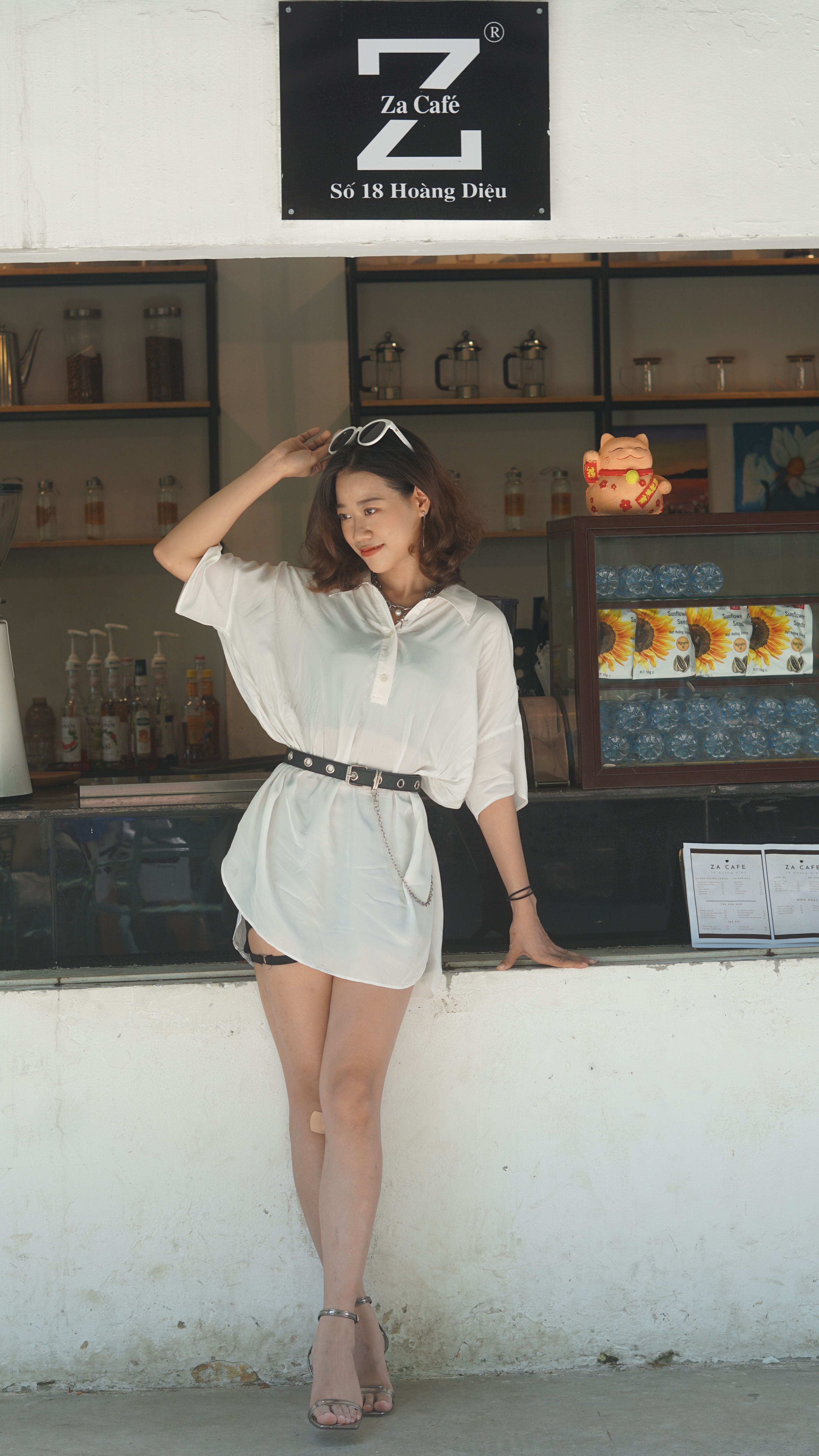 Stylish woman in chic outfit posing at a café, showcasing modern fashion trends and casual elegance.