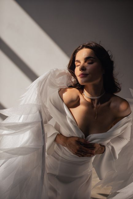 Elegant woman in a white dress with wings, captured in a warm, artistic light.