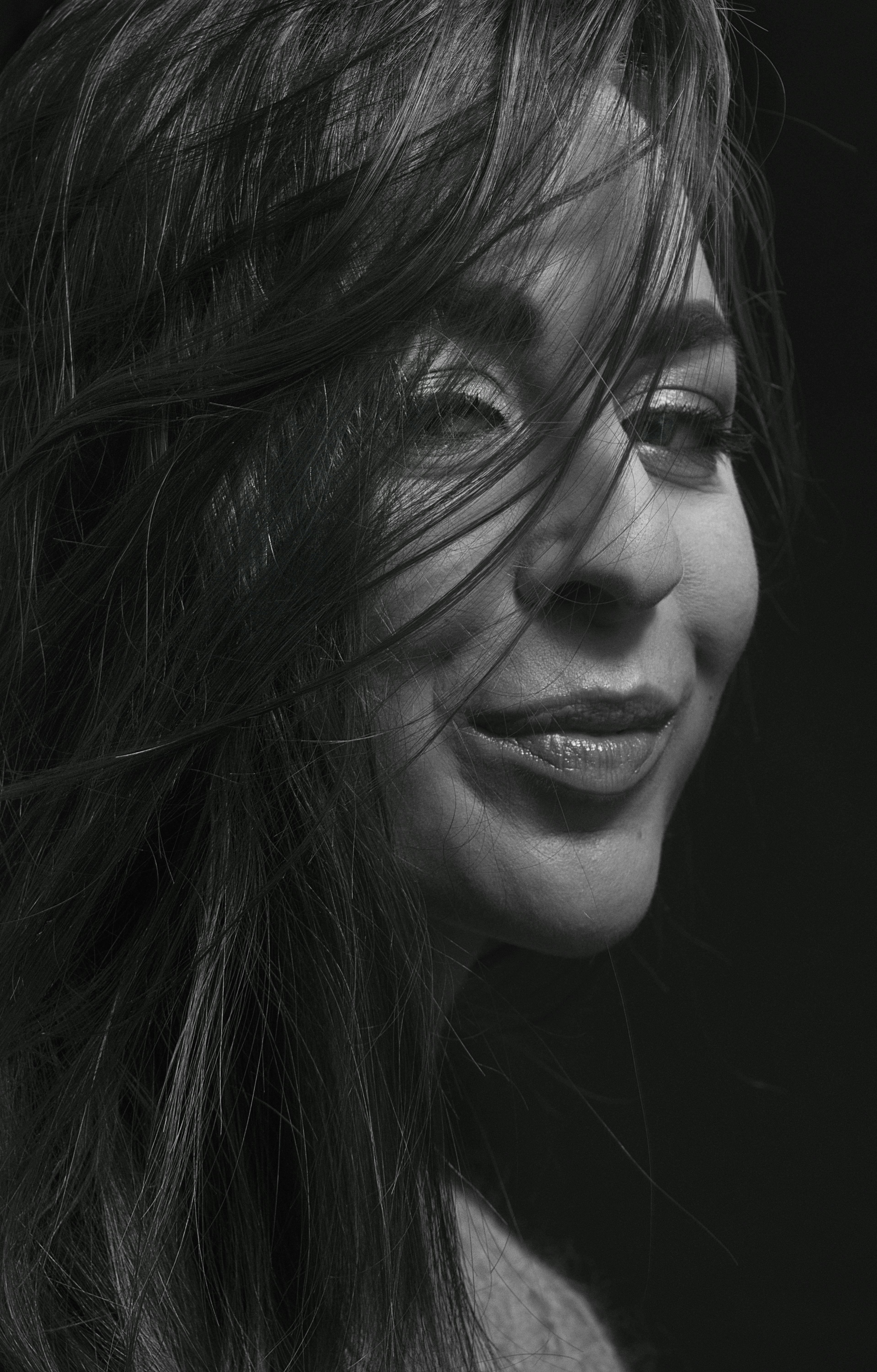 A captivating black and white portrait showcasing a woman's expressive smile and long hair.