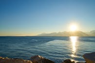 宁静的日出映照在多山的海景上，海水湛蓝清澈，倒影宁静