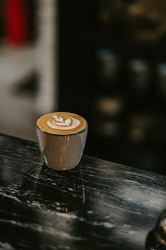 Elegant cappuccino with latte art served on a sleek marble table in a café setting.