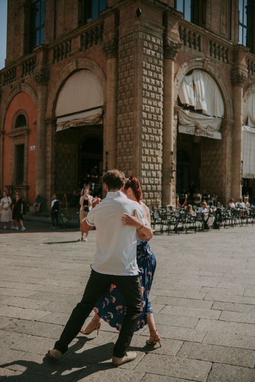 Free A couple dances gracefully in a sunlit urban square beside a historic building. Stock Photo