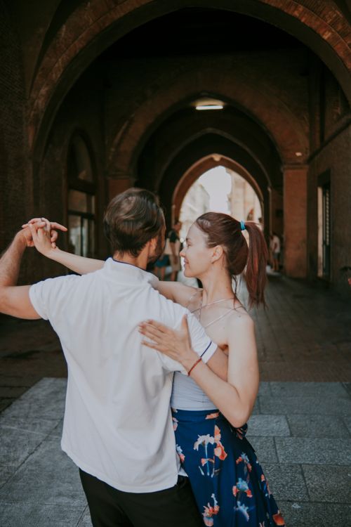 Free A couple joyfully dances under an urban archway, adding romance and elegance to the city backdrop. Stock Photo