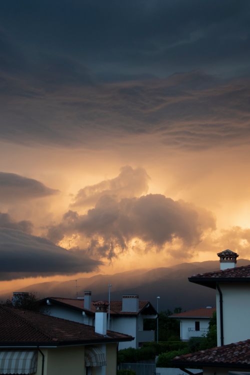 Free A stunning sunset over Roveredo in Piano, capturing dramatic clouds and urban rooftops. Stock Photo