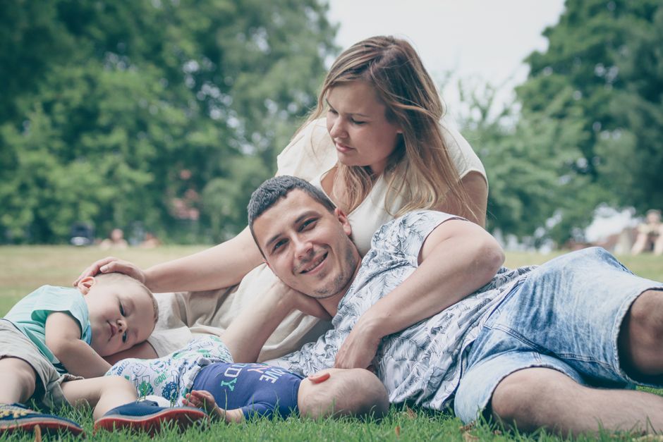 Happy family enjoying a sunny day outdoors, with parents and children lying on the grass.