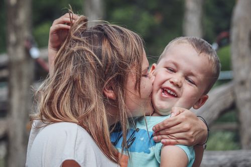 Free Joyful mother kissing her son in a playful outdoor scene, capturing love and happiness. Stock Photo