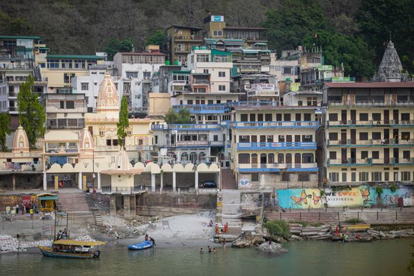 Scenic view of houses along the riverbank in Rishikesh, India - a picturesque riverside town known for its natural beauty and spirituality