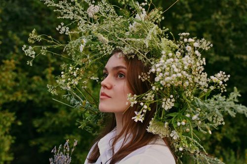 Free A woman adorned with a natural floral wreath in an outdoor rustic setting. Stock Photo