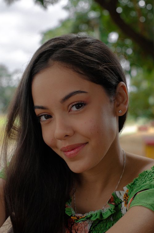 Free Close-up portrait of a smiling woman with long hair and green dress outdoors. Stock Photo