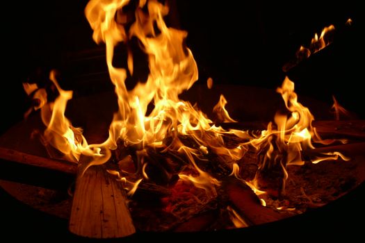 Close-up view of a glowing bonfire with wood logs and dancing flames.