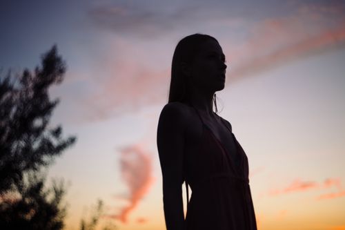 Free A striking silhouette of a woman against a vibrant sunset sky, capturing serene beauty. Stock Photo