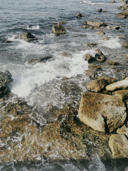 Free Waves splashing over rocky shoreline on a sunny day. Stock Photo