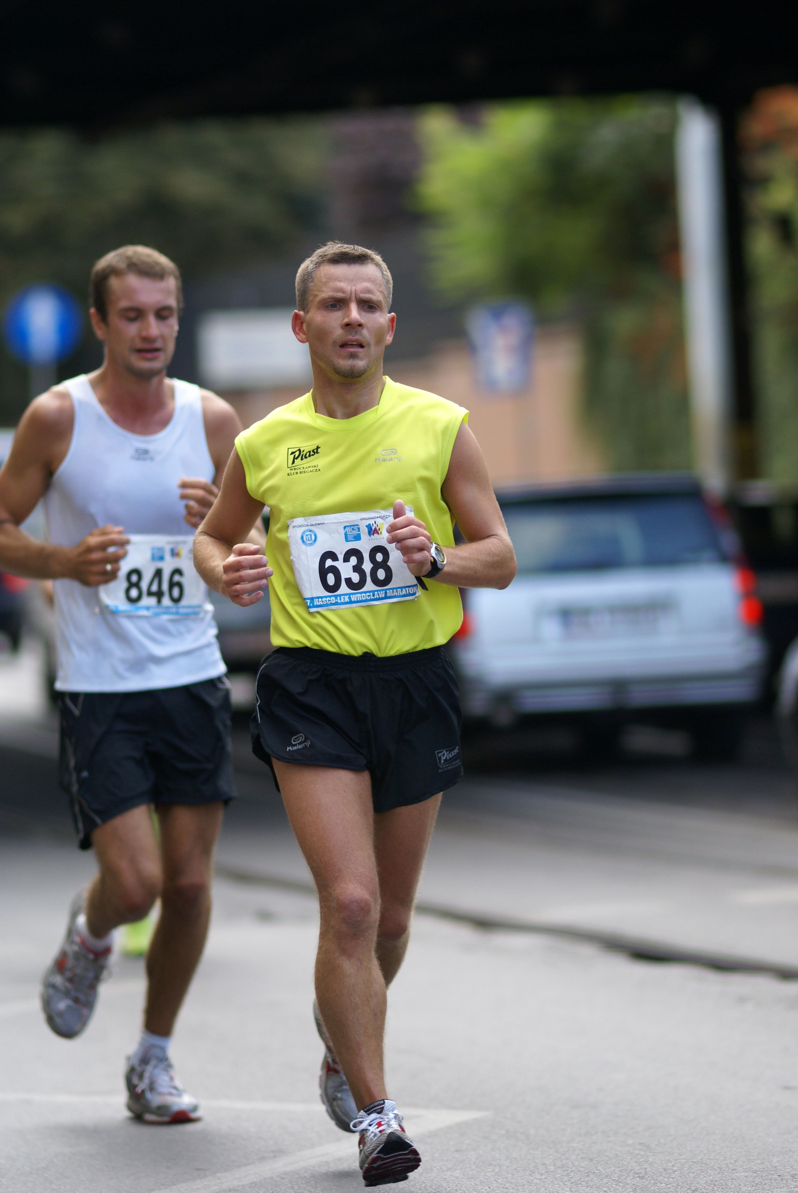 Two adult male runners participating in a city marathon, focused and determined.
