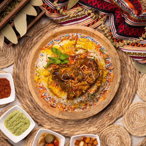 Free Top view of a flavorful biryani dish with vibrant spices and side condiments on a woven mat. Stock Photo
