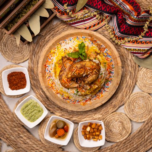 Free Delicious biryani with roasted chicken served with pickles and dips on a rustic setup. Stock Photo