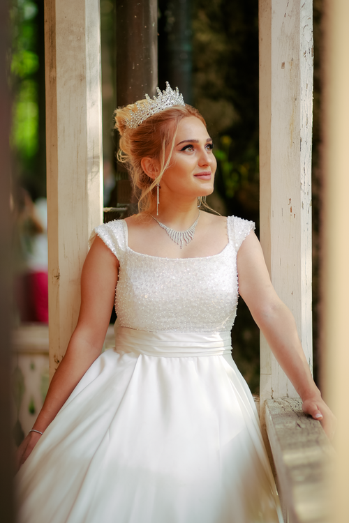 Free Beautiful blonde bride wearing a tiara and wedding dress in an outdoor setting. Stock Photo