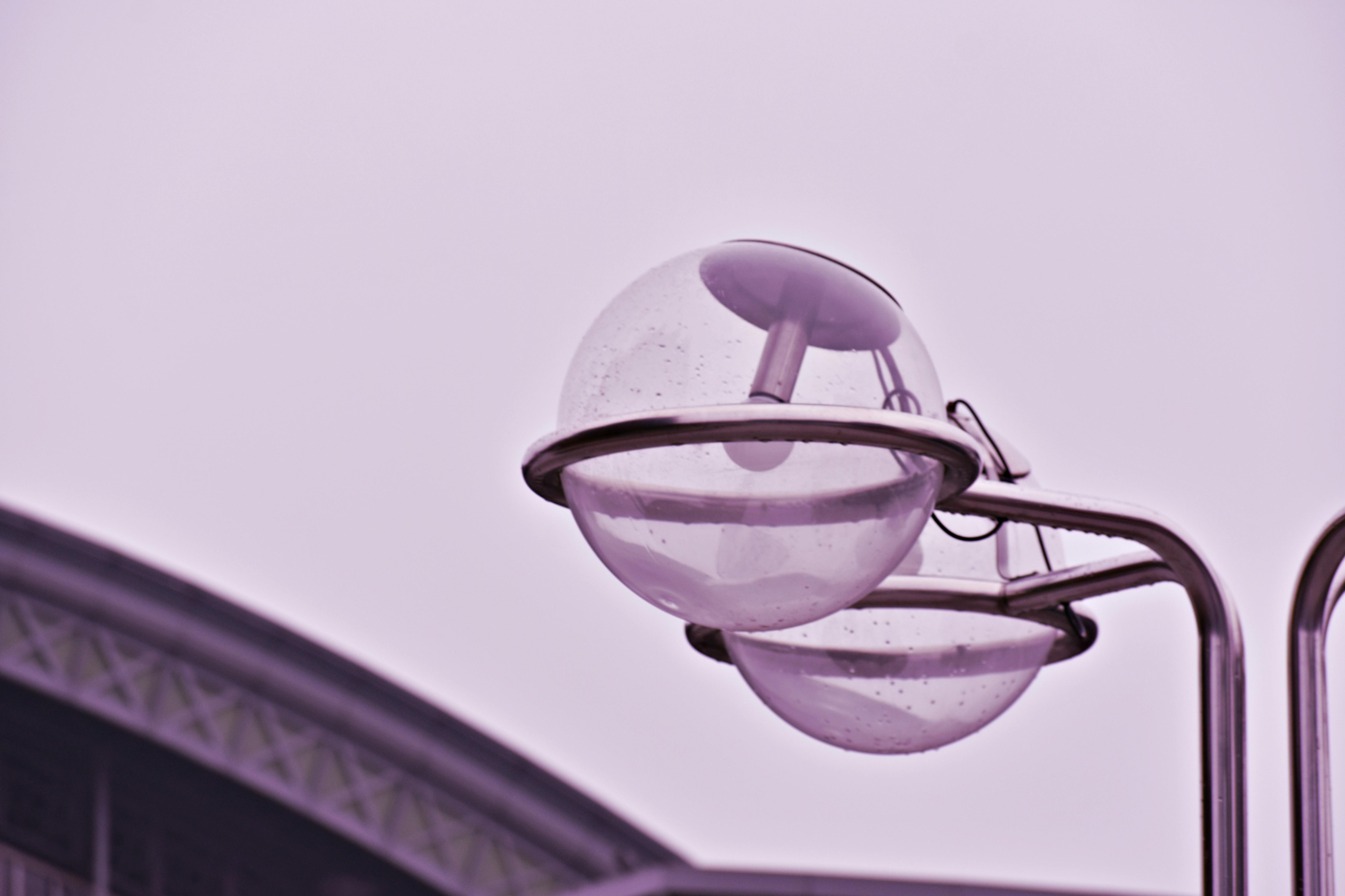 Close-up of modern globe lamps on a steel structure under overcast sky.