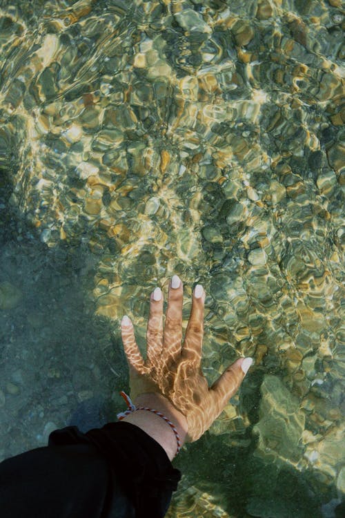 Woman Hand in Transparent Water on Sea Shore