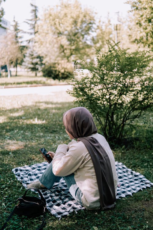 A Woman in Hijab Sitting on a Picnic Blanket