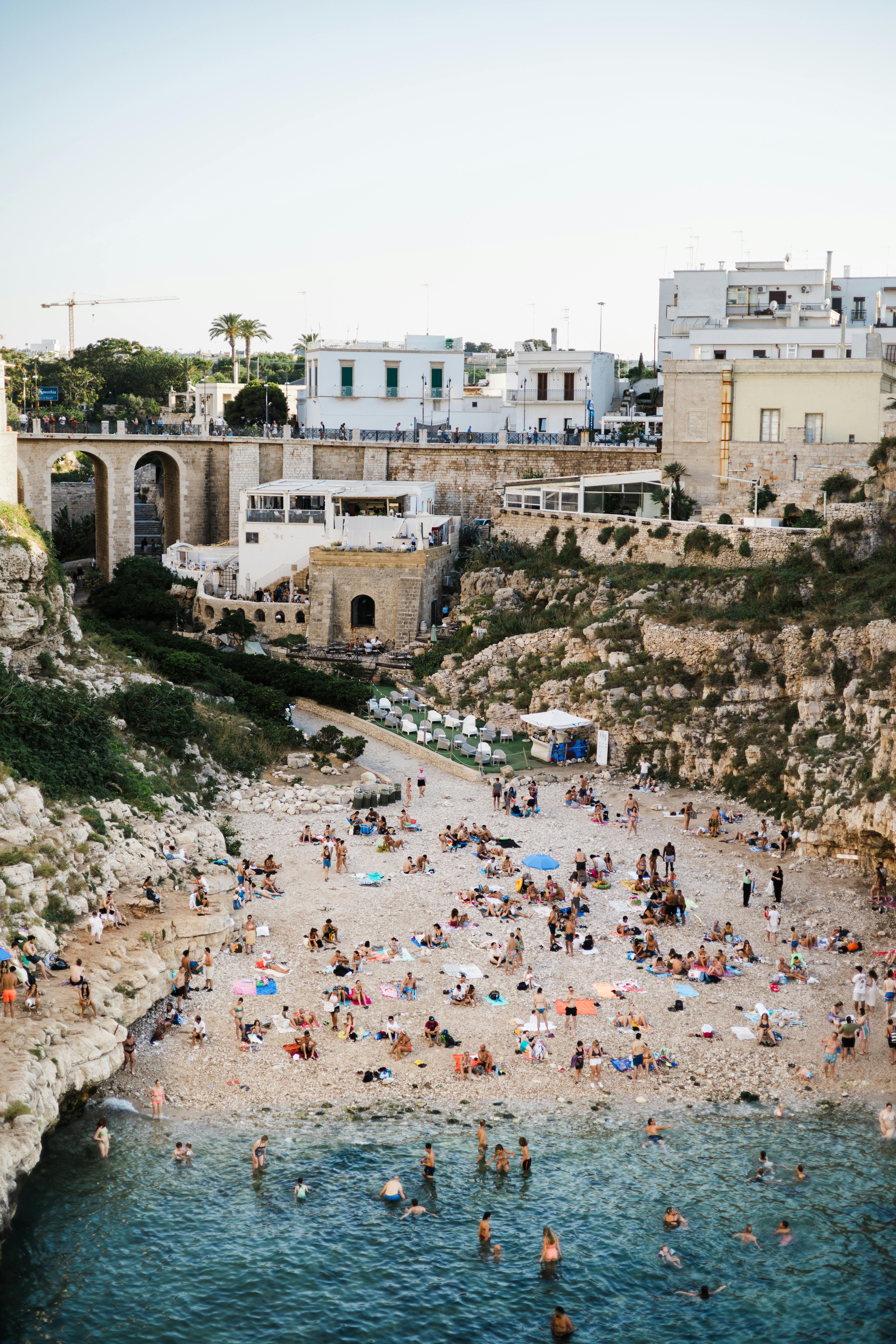 Aerial view of Polignano a Mare beach with tourists enjoying summer by the sea in Apulia, Italy.