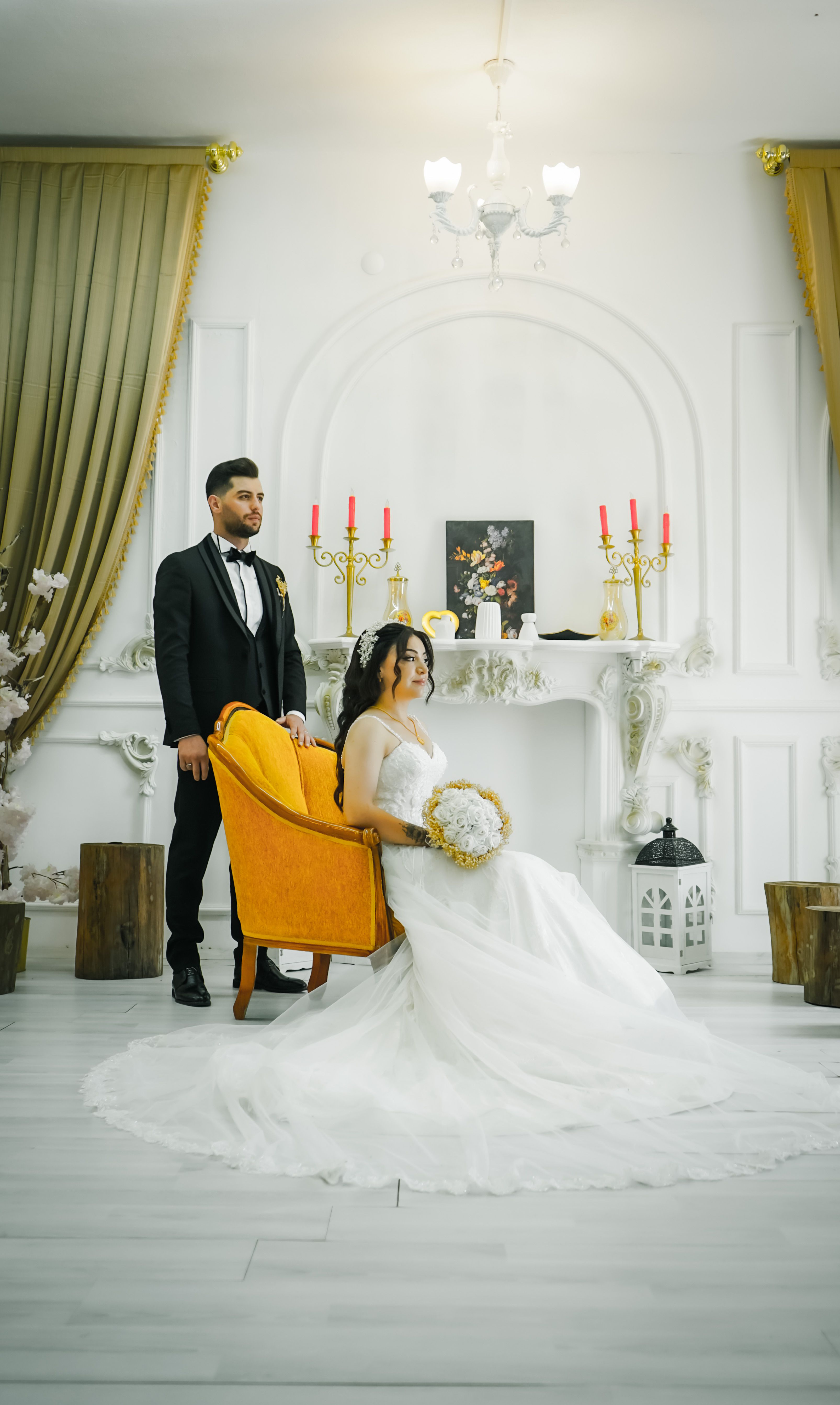 A stylish indoor wedding portrait featuring a bride in a gown and a groom in a tuxedo.