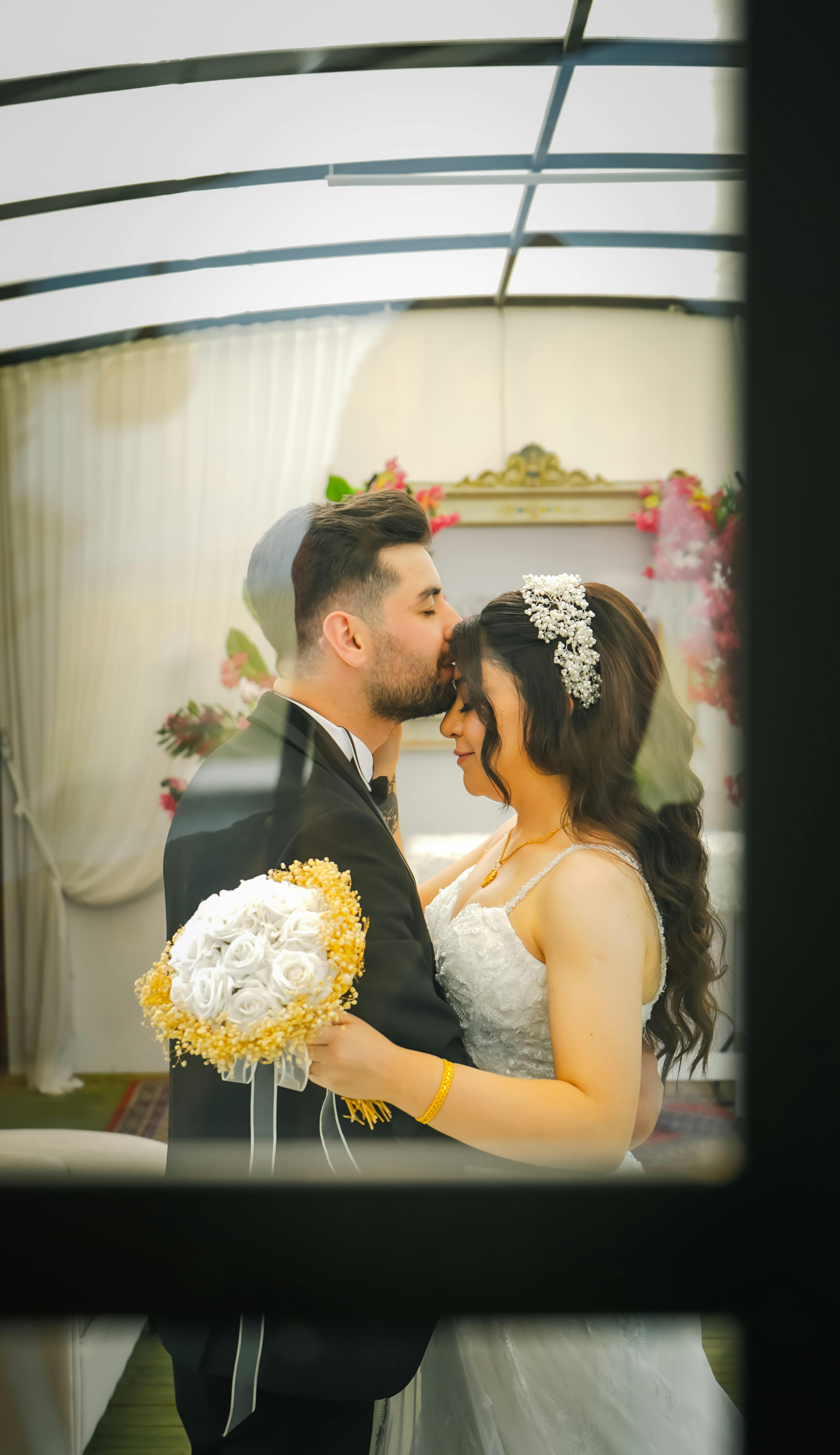 A romantic moment of a wedding couple embracing through a window.