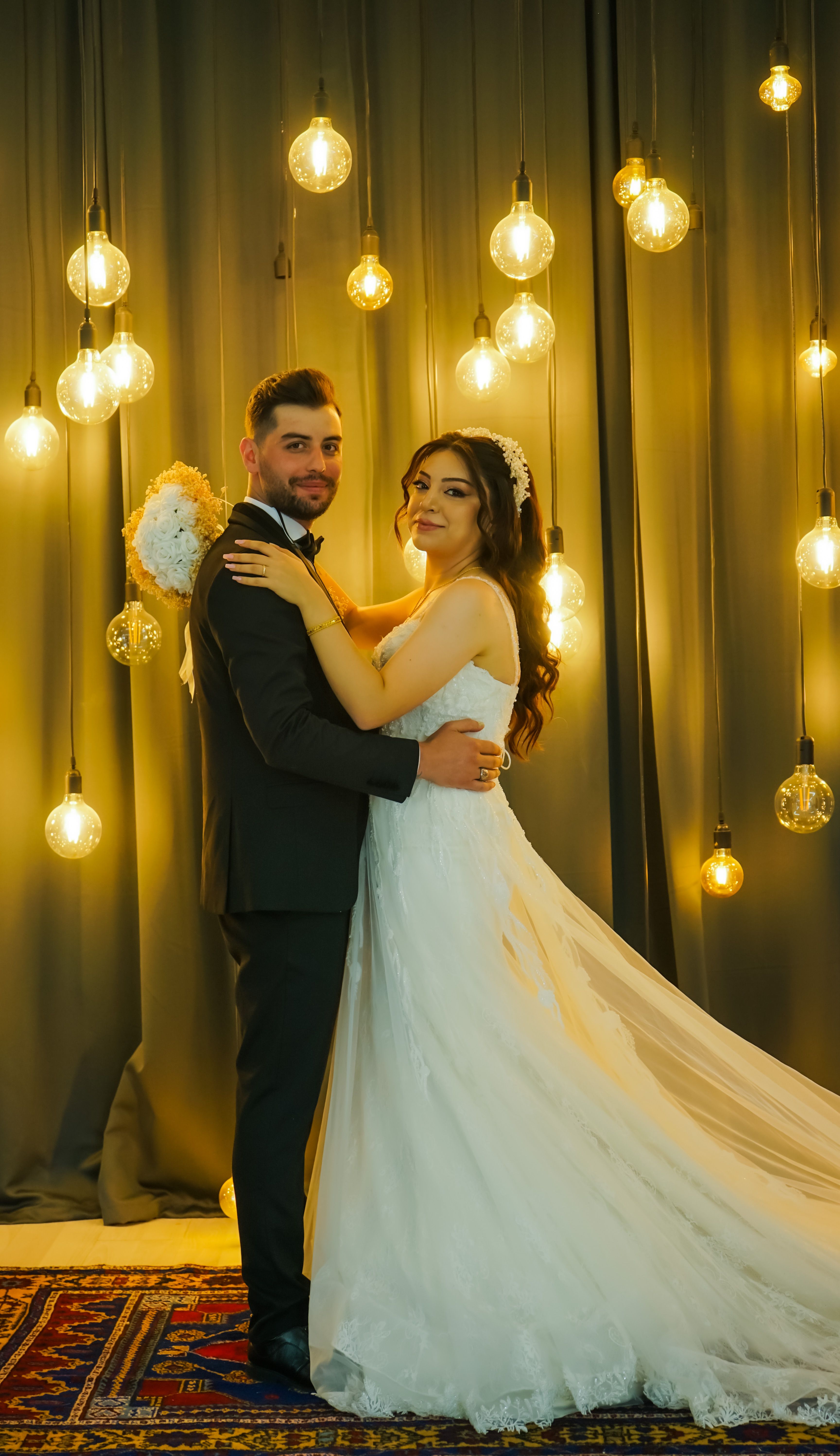 Bride and groom posing with hanging lights backdrop for a stunning wedding portrait.