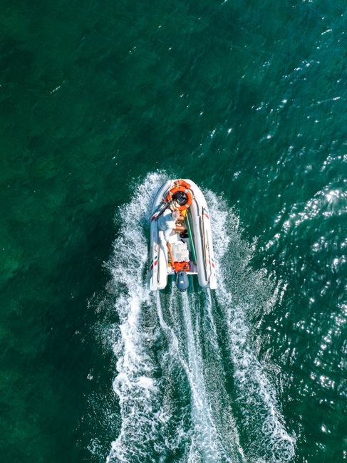 A captivating aerial shot of a motorboat navigating the vibrant turquoise sea near Torre Canne, Italy.