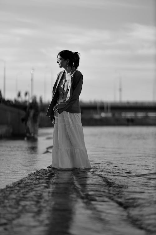 Woman in Jacket and Skirt Standing in Shallow Water