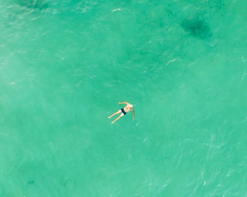 Free Top view of a person swimming in the clear blue sea near Monopoli, Italy, on a sunny day. Stock Photo