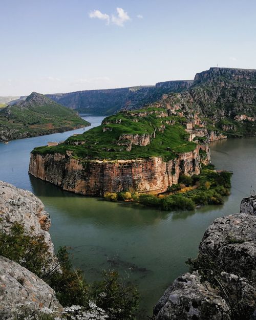 Free Captivating view of a towering cliff surrounded by a calm river, perfect for nature lovers. Stock Photo