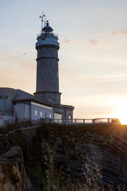Free A captivating view of a lighthouse at sunset, highlighting coastal scenery and guidance for ships. Stock Photo