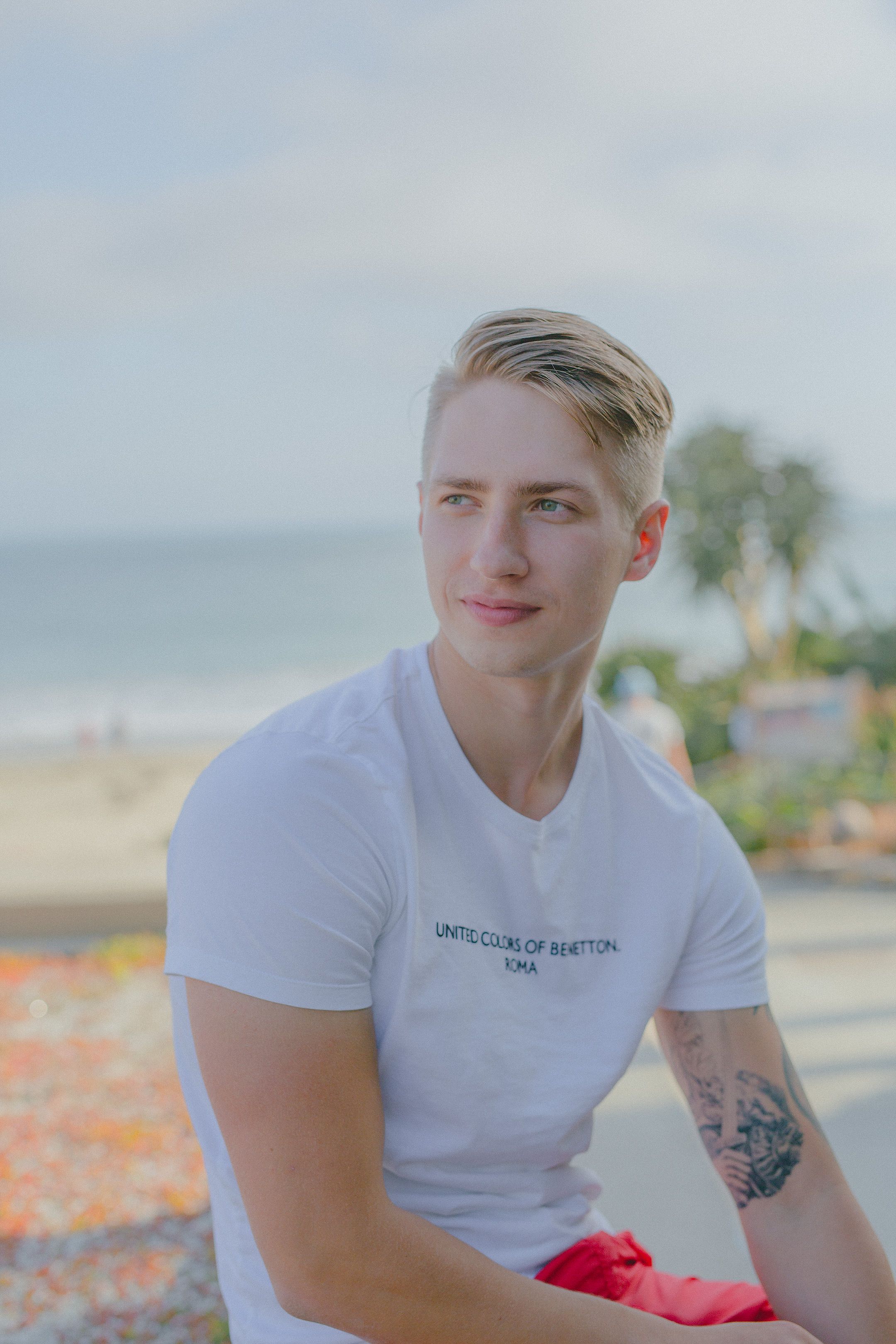 Portrait of a young man with tattoos enjoying a sunny day by the beach.