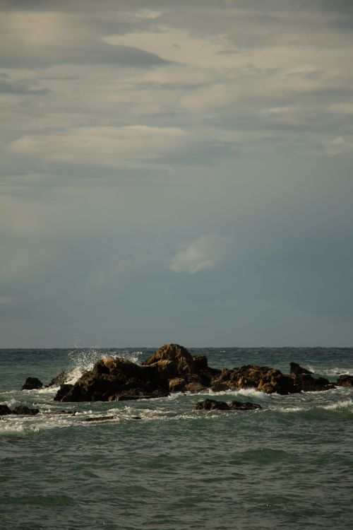 Free Scenic view of waves crashing against rocks under a moody sky at dusk. Perfect for travel and nature themes. Stock Photo