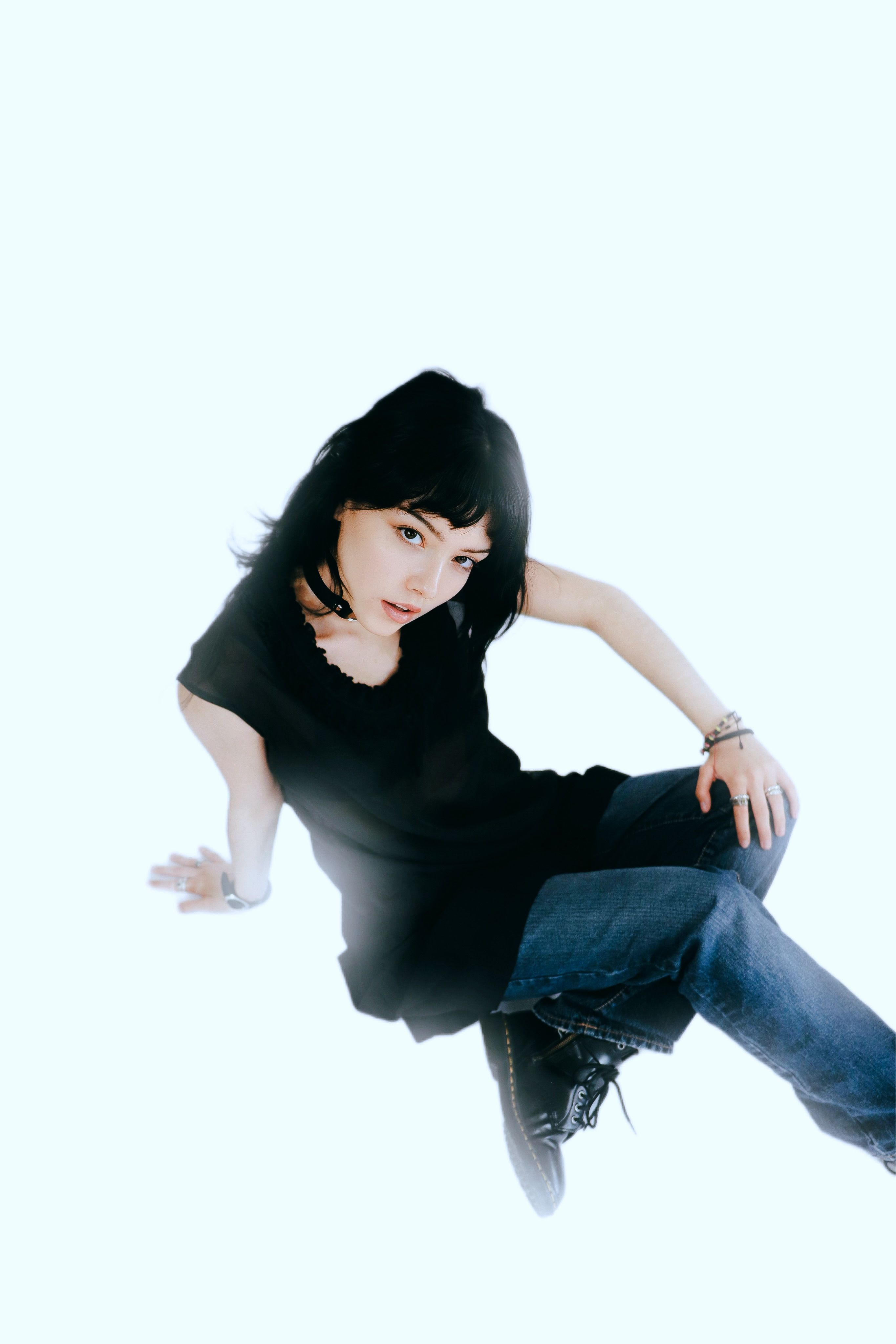Stylish woman in black outfit posing against a bright background, showcasing contemporary fashion.