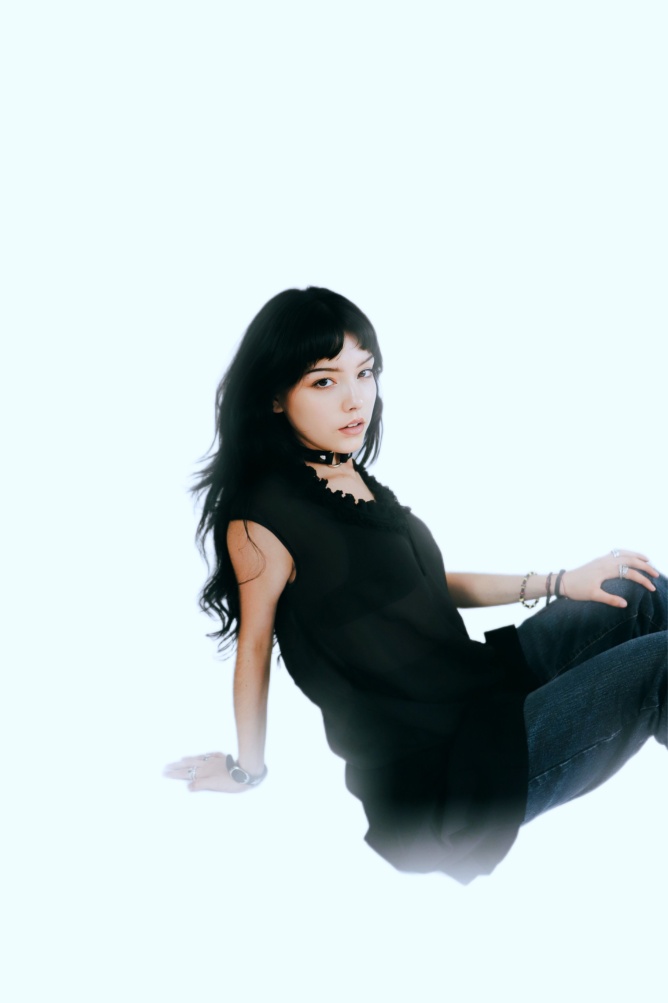 Stylish woman with black hair in a modern fashion pose on a white background.
